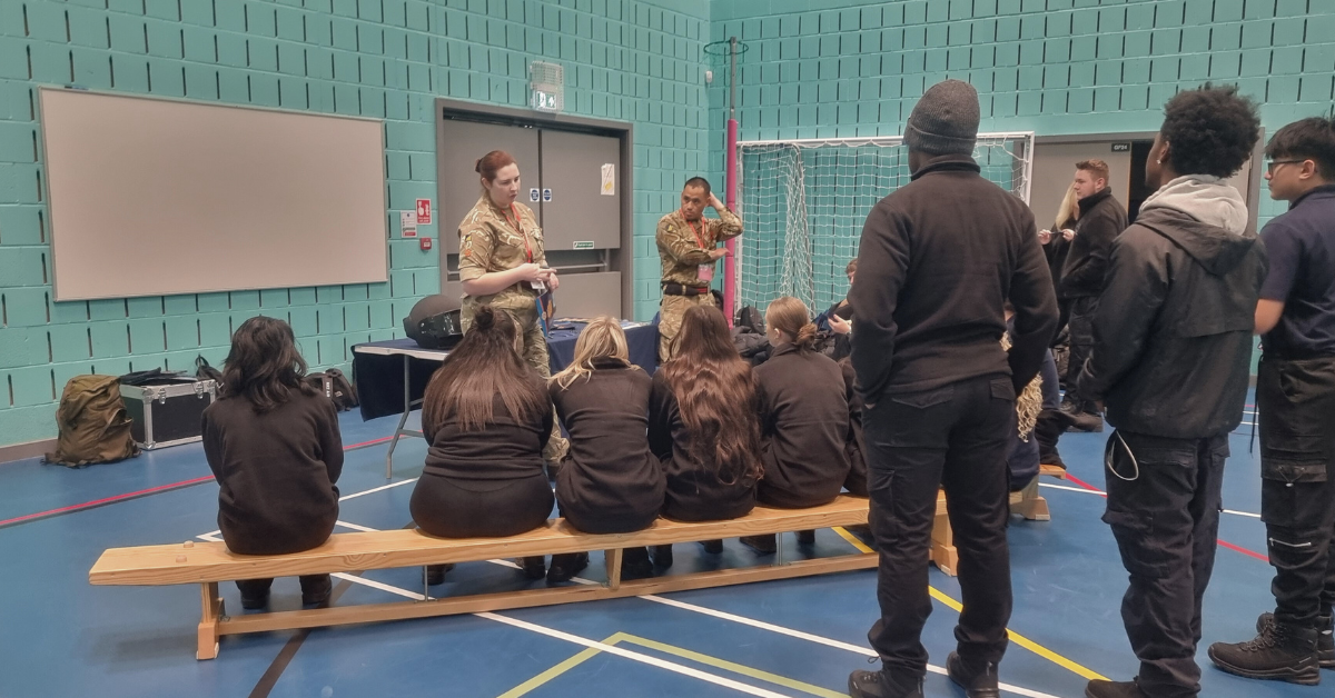 A group of students sat on a bench hearing a talk from the logistics core of the army